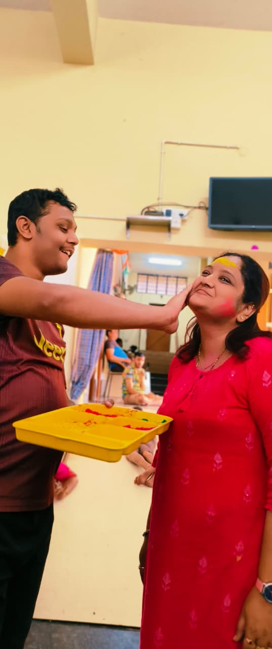 Student applying colour to a staff member during Holi celebrations